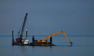 Дноуглубительная баржа с грейферным краном у портовых причалов